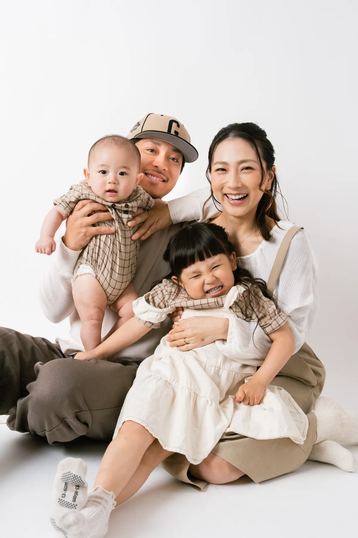 白背景で寄り添って笑うご家族4人の記念写真