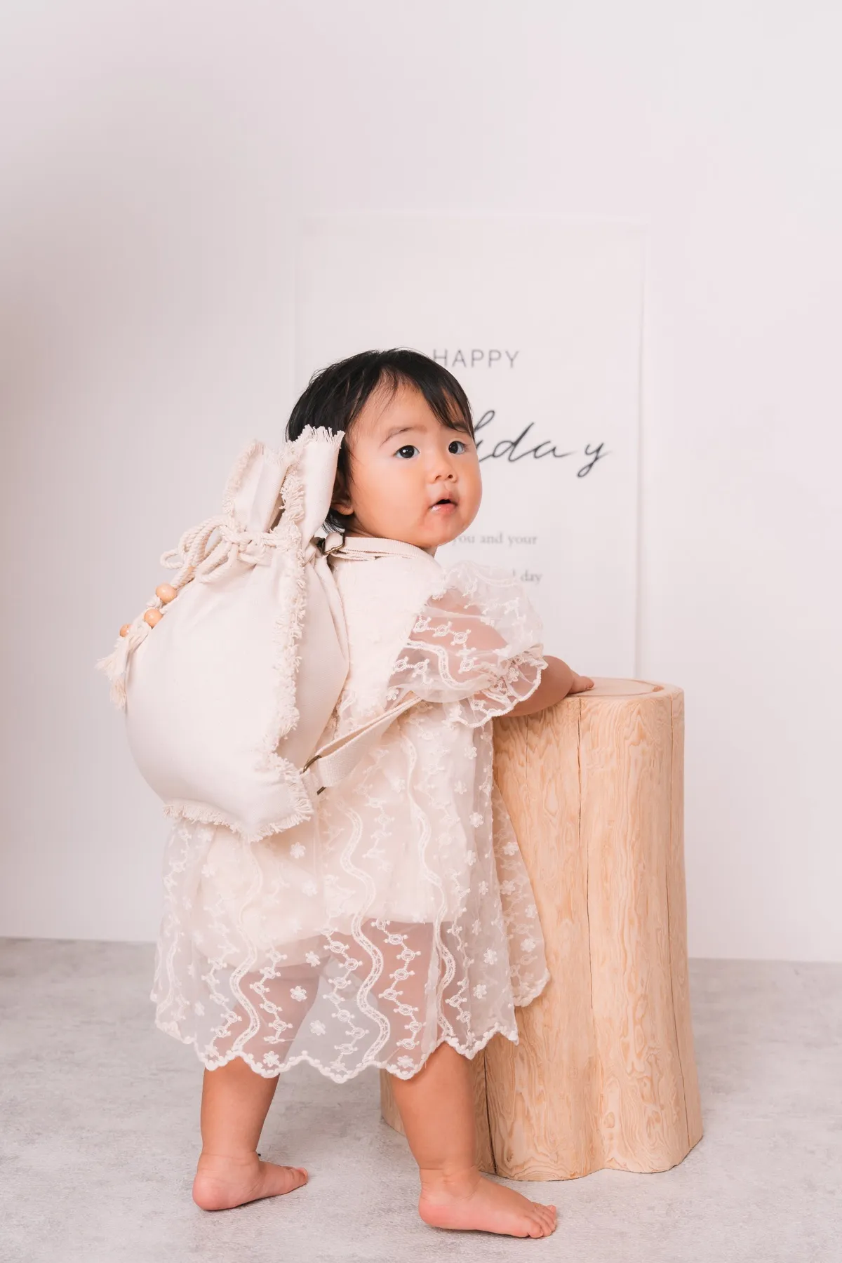 一升餅のリュックを背負ってつかまり立ちする1歳の女の子