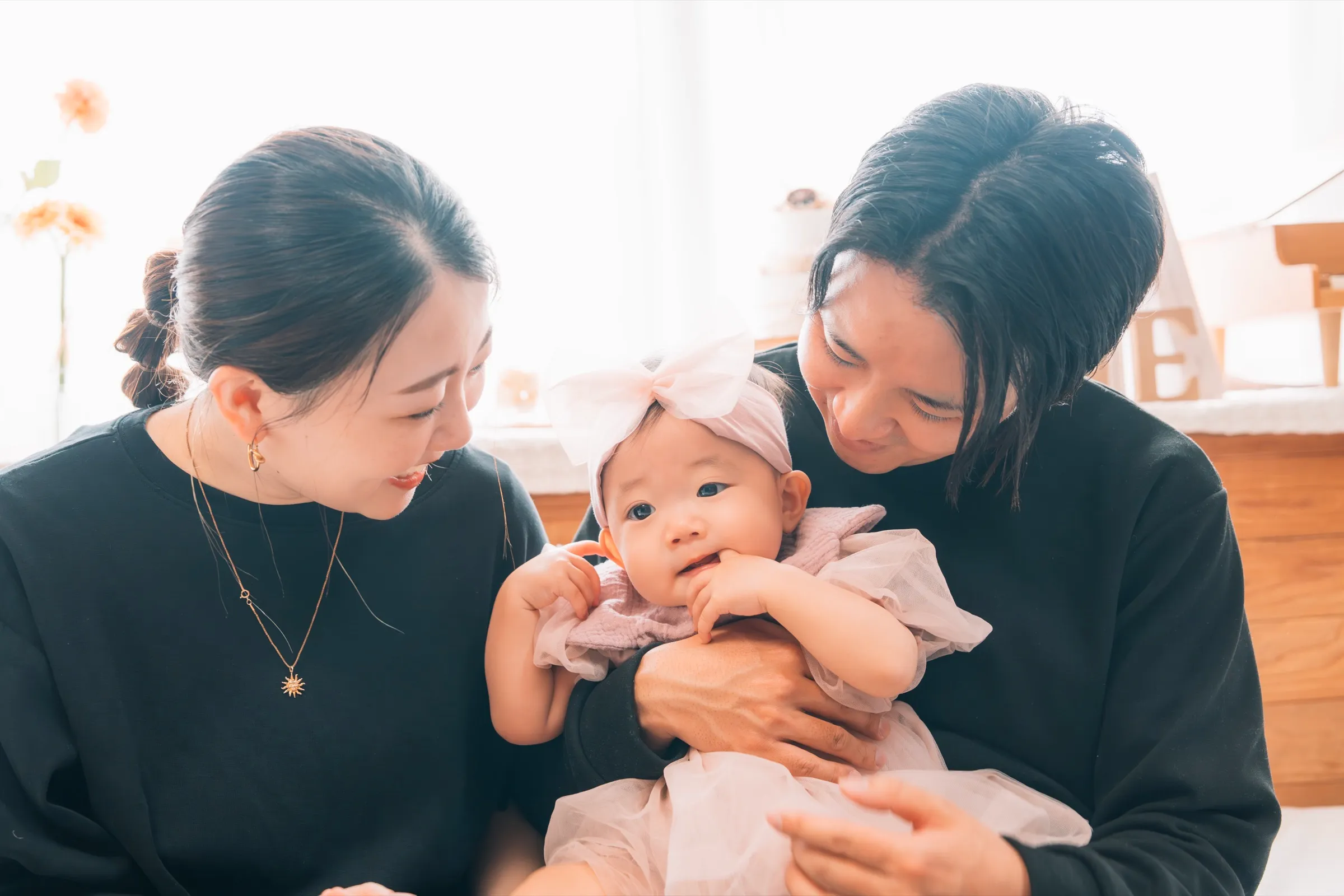 自然光の入る貸切スタジオで、赤ちゃんを囲んで微笑むご家族